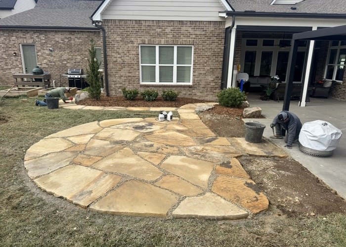 Hewitt Landscape crew at work beside new shrub plantings and a flagstone patio at a brick home